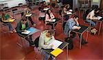 Students taking notes in class with one girl smiling up at camera at the university