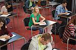 Students taking notes in classroom with one blonde girl looking up at the university