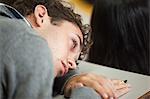 Male student resting his head in a lecture hall in college