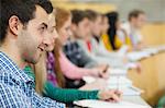 Row of smiling students listening in a lecture hall in college