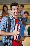 Happy student standing in front of his class in lecture hall smiling at camera in college