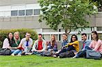 Group of students smiling at camera on the grass on campus at the university