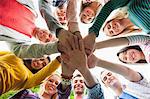 Group of happy students putting hands in a circle on campus at the university