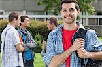 Happy student smiling at camera in front of his classmates at the university