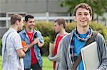 Cheerful student smiling at camera in front of his classmates at the university