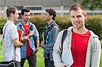 Cheerful male student smiling at camera in front of his classmates at the university