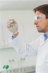 Profile view of young male scientist looking at small test tube in laboratory