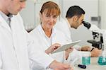 Female mature scientist using her tablet in the laboratory while smiling at camera