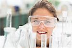 Cheerful student wearing safety glasses in front of test tubes in lab at college