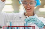 Smiling student using pipette holding test tube in lab at college