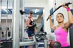 Calm brunette training at weight machine in weights room of gym