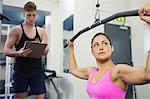 Determined brunette training at weight machine in weights room of gym