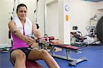 Sporty woman training arms on weight machine in weights room of gym