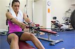 Determined woman training arms on weight machine in weights room of gym