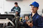 Smiling trainee showing part of a machine in workshop