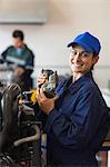 Cheerful trainee showing part of a machine in workshop