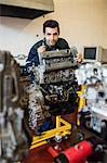 Content repairman standing behind an engine in workshop