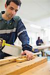 Serious carpenter sawing wood in workshop