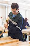 Carpenter using mallet and chisel in workshop