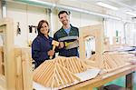 Happy trainee and instructor standing behind construction in workshop