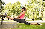 Rear view of a flexible young woman doing the splits exercise in the park