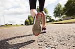 Close up low section of a sporty young woman jogging on pathway in the park