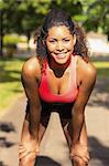 Tired healthy young woman taking a break while jogging in the park