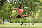 Full length of a toned young woman performing the splits jump in the park