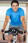 Portrait of a smiling young man working out at spinning class in gym