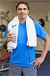 Portrait of a smiling young man with water bottle standing in the gym