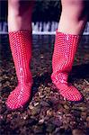 Close up low section of a woman in pink gumboots standing on pebbles