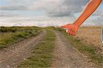 Close up of a woman hitchhiking on dirt countryside road