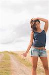 Portrait of a cool young woman hitchhiking on dirt countryside road