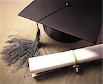 Graduation cap with diploma over the table. Clipping path included.