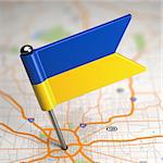 Small Flag of Ukraine Sticked in the Map Background with Selective Focus.