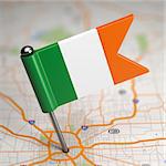 Small Flag of Ireland Sticked in the Map Background with Selective Focus.