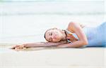 Young woman in swimsuit laying on sea shore