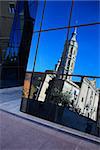 Modern glass wall with reflection of old church against blue sky