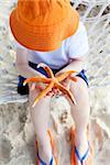 close-up of bright orange starfish, little boy holding it in his hands at the beach sitting in the hammock