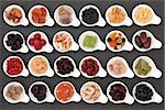 Large dried fruit selection in white bowls over slate background.