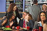 Four businesspeople laughing together during lunch in cafe