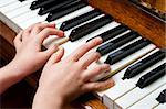 Llittle girl trying to play the piano with her little fingers.
