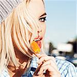Portrait of beautiful girl with blond loose hair and smokey eye makeup licks ice cream with her tongue in a sexy way