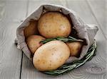 baby potatoes in sack bag with rosemary on wood table