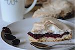 This is a cake stuffed with cornel-berry jam and covered with meringue. The tart is situated on white plate and decorated with berries.