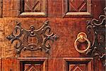 Closeup of old ornate wooden door with a gold door handle in Alba, Italy.