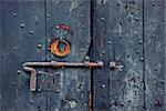 Closeup image of old wooden door with metal knob and rusty bolt.