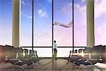Businessman standing with hands in pockets against airplane flying past departures lounge