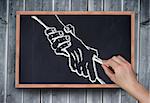 Composite image of hand drawing handshake with chalk on chalkboard on grey wooden planks
