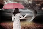 Businesswoman holding umbrella against stormy sky with tornado over field